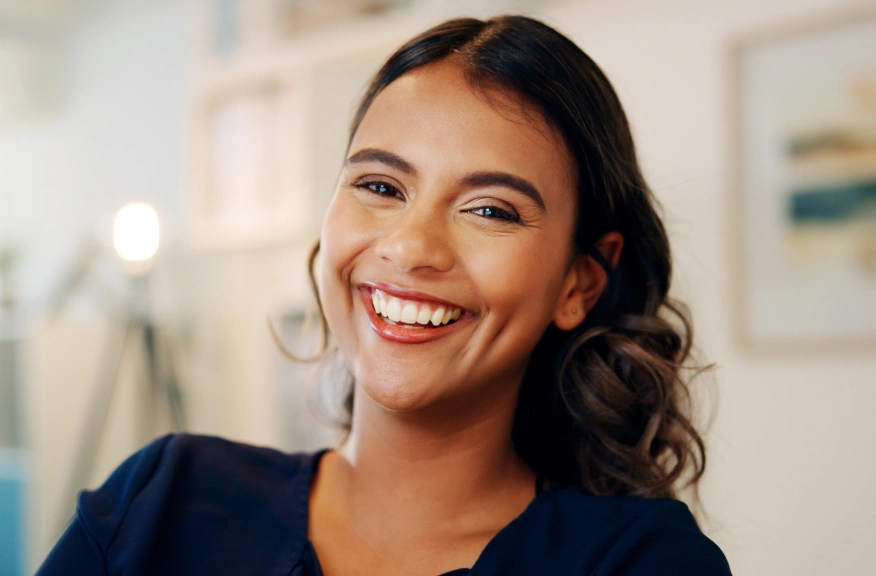 Smiling dental professional in scrubs at modern dental office reception area.