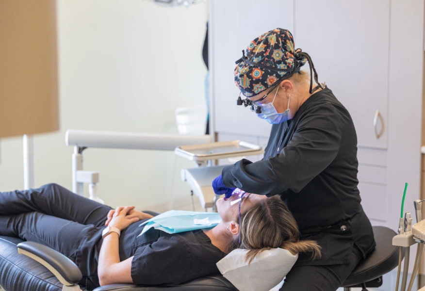Dentist examining patient's teeth in clinical treatment room at Boyd Family Dentistry office.