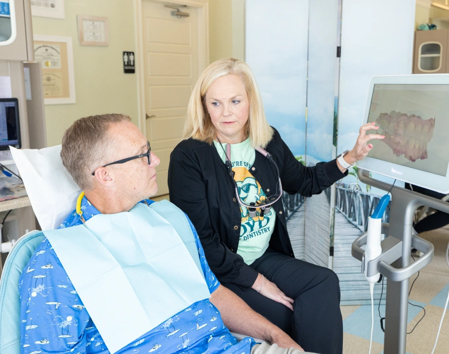Dentist showing patient dental X-rays in modern dental office treatment room.
